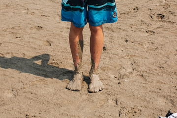 Closeup of the man's muddy feet on the beach.