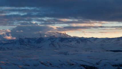 Fototapeta na wymiar Elbrus in the clouds in the light of the sunset rays