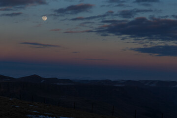 The moon in the setting cloudy winter sky