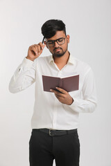 Young indian man holding diary in hand and thinking some idea.