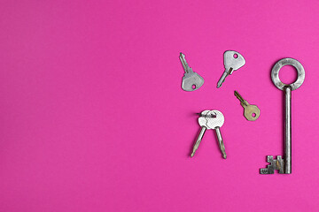Keys on pink background, flat lay, trendy colorful photo with colored paper. Copy space.