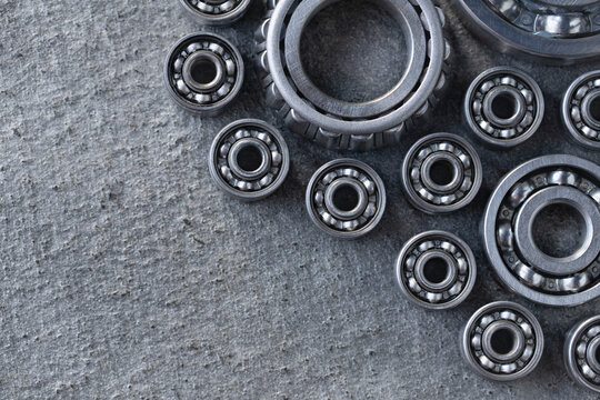 Set Of Deep Groove Ball And Roller Bearings On A Gray Background With Space For Text. Top Flat Top View Of Axial Lubricated Bearings For Heavy Machinery And Mechanical Engineering With Copy Space.