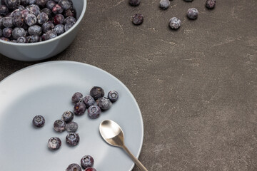 Frozen blueberries and spoon on gray plate. Frozen blueberries in gray bowl.
