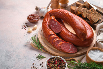 Smoked, Krakov sausage on a cutting board with bread, garlic and spices on a light background.