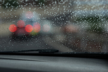 Drizzle on the windshield in the evening. Abstract traffic in rainy day