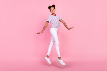 Fototapeta na wymiar Full length photo of brown bun haired african american stylish trendy girl wear casual clothes jump walk isolated on pink color background