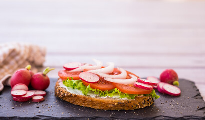 Dietetic snack with a slice of whole grain bread with cheese, lettuce, tomatoes and onion. Copy space