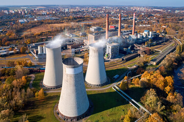 Aerial view of typical coal thermal power plant complex with cooling towers in operation and city...