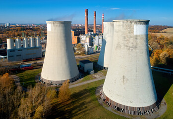 Aerial view of cooling towers of a thermal power plant with three chimneys against city in the...