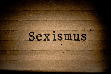 Gestempelter Text auf zerknittertem Pappkarton. Sexismus.