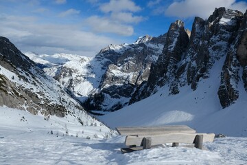 Beautiful mountain viewpoint with wooden bench in snowy scenery. During trip in Dolomites around Tre Cime. Sexten Dolomites, South Tyrol, Italy