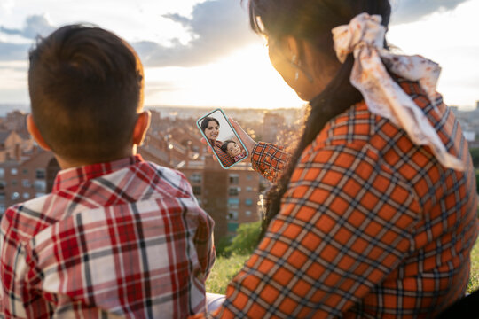 Woman and son taking selfie through mobile phone on hill