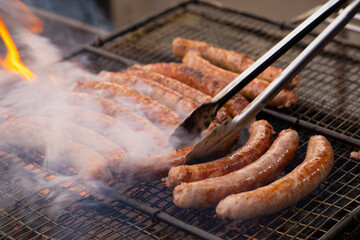 Butifarras (botifarra) a la brasa o parrilla (embutido fresco) humeando (humo) al fuego