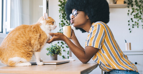 Woman puckering while looking at cat on desk