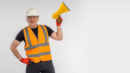 Worker with megaphone in his hands. Person in a construction uniform holds a loudspeaker. Worker reports need for repairs. Repair adv. Place for text. Construction advertising. Smiling foreman