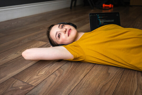Woman with headphones day dreaming while resting on floor at home