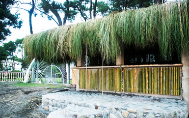 Typical bamboo hut and palm leaves standing at the white sand beach against background with beautiful sea and cloudless blue sky on a sunny day. Panglao Island, Philippines.