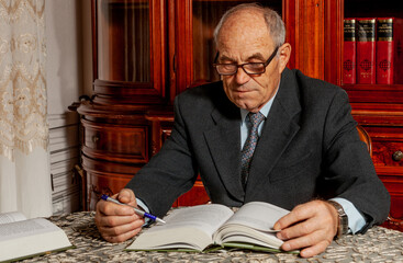 Portrait of senior professor sitting at desk, reading book