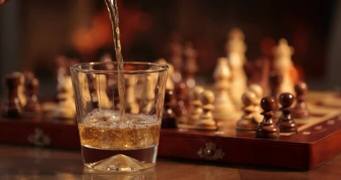 Cognac, whiskey, bourbon poured into a glass against the background of a fire in the fireplace. Warmth and home comfort. 4K