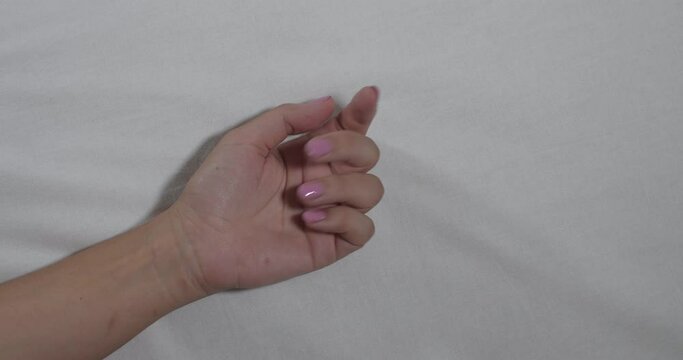 A close-up of the hands of an unrecognizable man and woman making love on a white sheet. Romance and humiliation concept