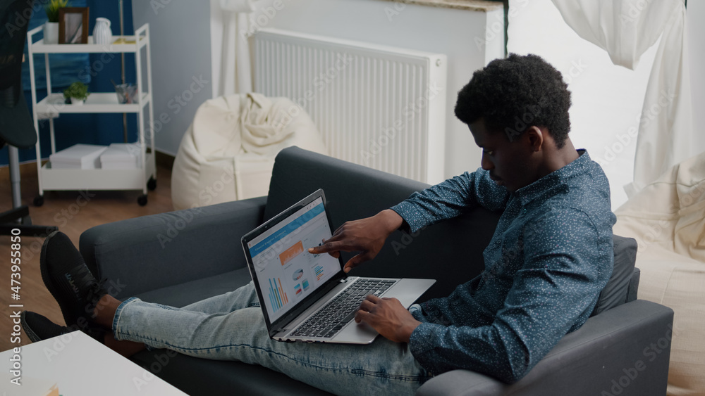 Aufkleber african american man working from home, remote working on laptop computer with online graphs and sta