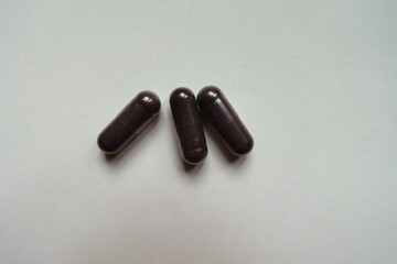 3 dark purple capsules of bilberry extract dietary supplement