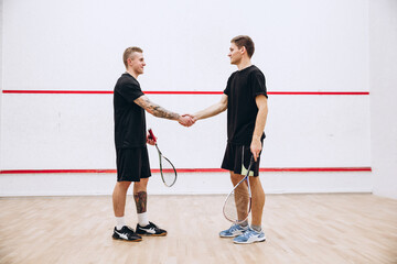 Full-length portrait of two young sportive boys shaking hands after game isolated over studio...