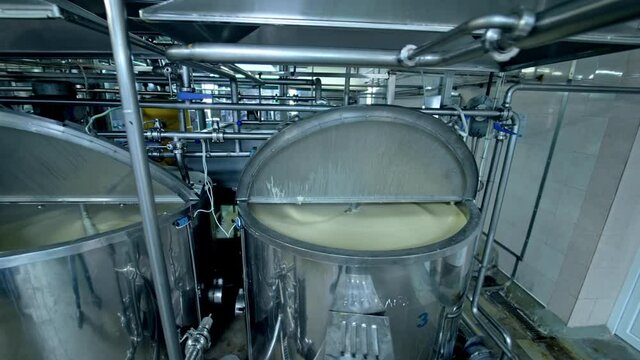 Three silver tanks for mixing milk products. Dairy production at the modern food factory. Steel tanks with open lids standing in row.