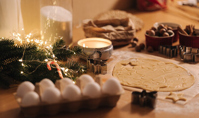 Raw dough for cooking Christmas cookies gingerbread on wooden table. Candle light at evening time