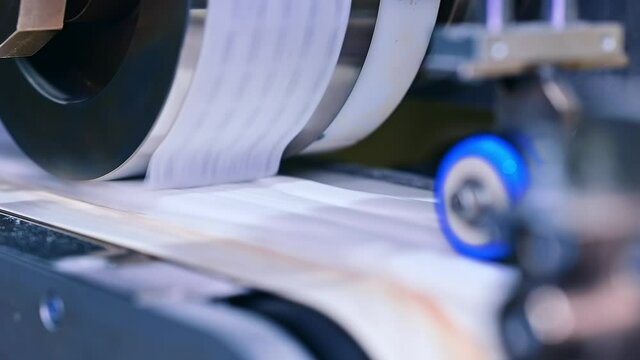 Roller rotating and sending the pieces of tissue on the conveyor belt. Automated system for modern production of dipers. Close up.