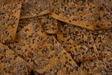 cereal cracker, rectangular bread or cookies with seeds and different seeds on a wooden background close-up
