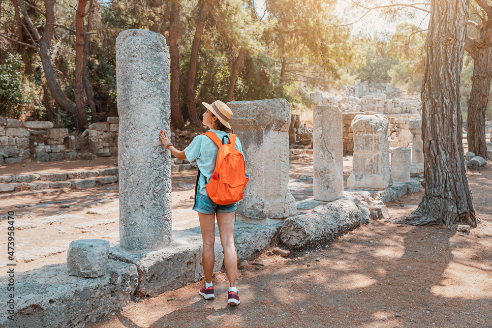 Wall mural female traveler walks through the ancient ruins of the antic greek city of phaselis in turkey. histo