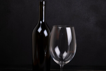 Wine bottle and glass on a black background close-up .Concept of alcoholism, addiction or loneliness