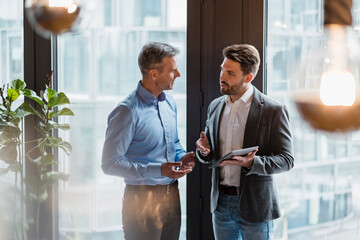 Male professionals discussing over digital tablet in office