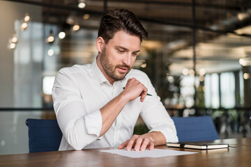 Male professional analyzing document over table at work place