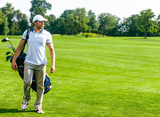 Young Male Golfer carries a Bag of Golf Clubs. Slim Man in White T-shirt , Golf Shoes, White Cap...