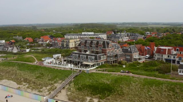 Aerial shot flying over the beach and approaching the historic bathing pavilion of the city of Domburg in Zeeland, the Netherlands, on an overcast summer day