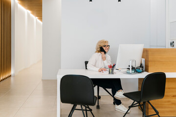 Mature receptionist talking on mobile phone at dentist's office