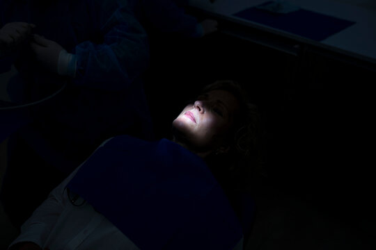 Doctors by patient in dark dental clinic