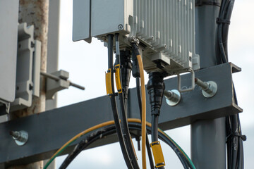 Fifth-generation base stations close-up. A large number of wires coming out of the radio module. Telecommunication pole of 4G and 5G cellular. Macro Base Station.