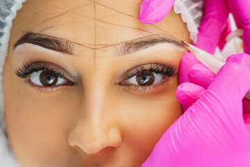  Permanent makeup, tattooing of eyebrows. Cosmetologist applying make up