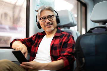 Senior man traveling by train. Man listening the music while enjoying in travel..