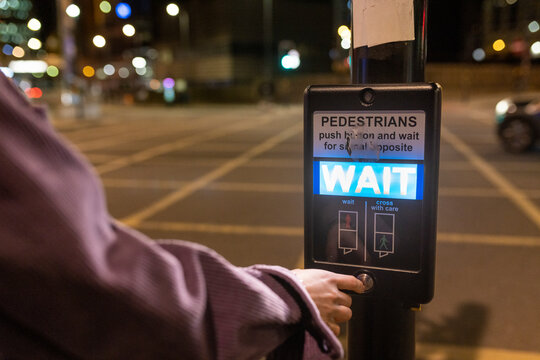 Woman pressing button on pedestrian walkway at night
