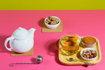 Tea in a cup in a composition with pastries and dessert, on a bright colored background.