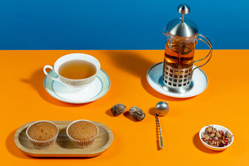 Tea in a cup in a composition with pastries and dessert, on a bright colored background.
