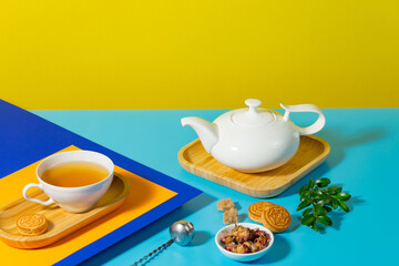 Tea in a cup in a composition with pastries and dessert, on a bright colored background.