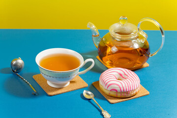 Tea in a cup in a composition with pastries and dessert, on a bright colored background.
