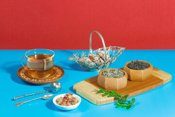 Tea in a cup in a composition with pastries and dessert, on a bright colored background.