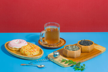 Tea in a cup in a composition with pastries and dessert, on a bright colored background.