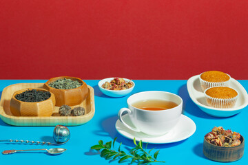Tea in a cup in a composition with pastries and dessert, on a bright colored background.